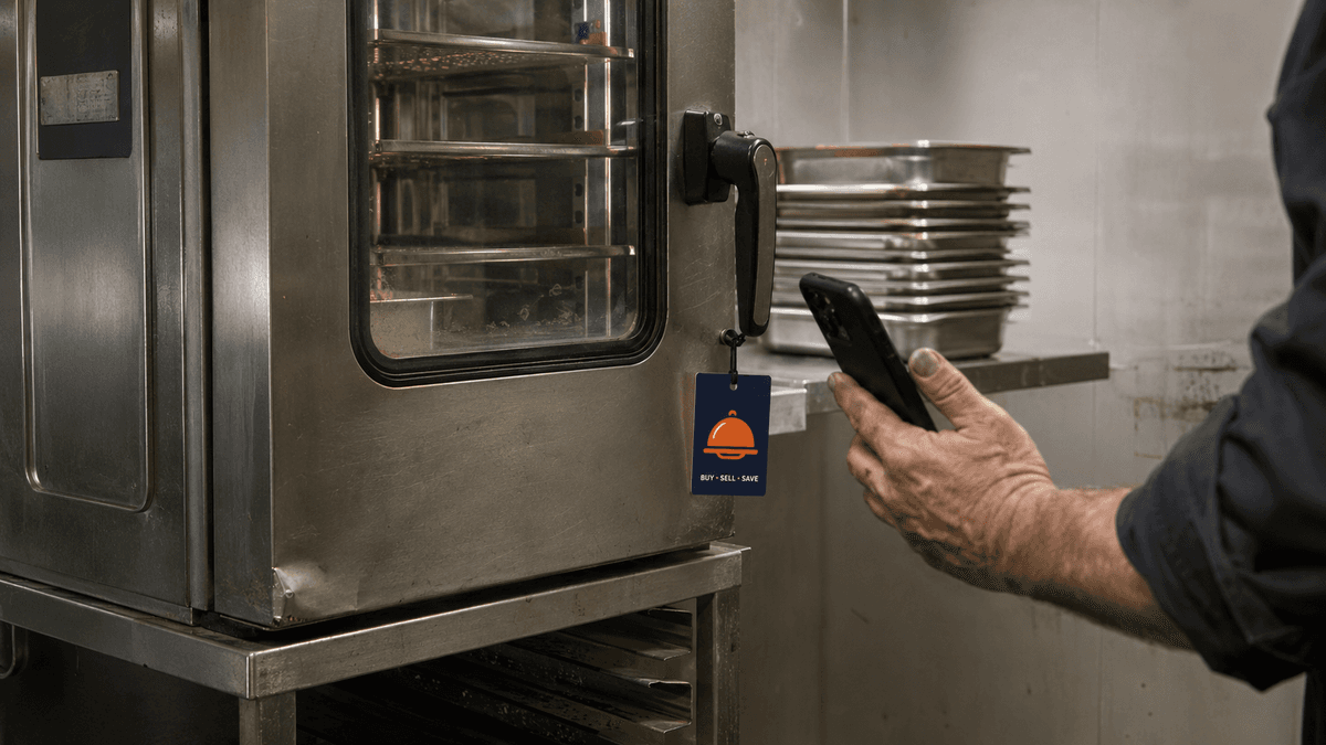 Used commercial combi oven still installed in a UK kitchen, with a seller checking listing options on their phone beside it.